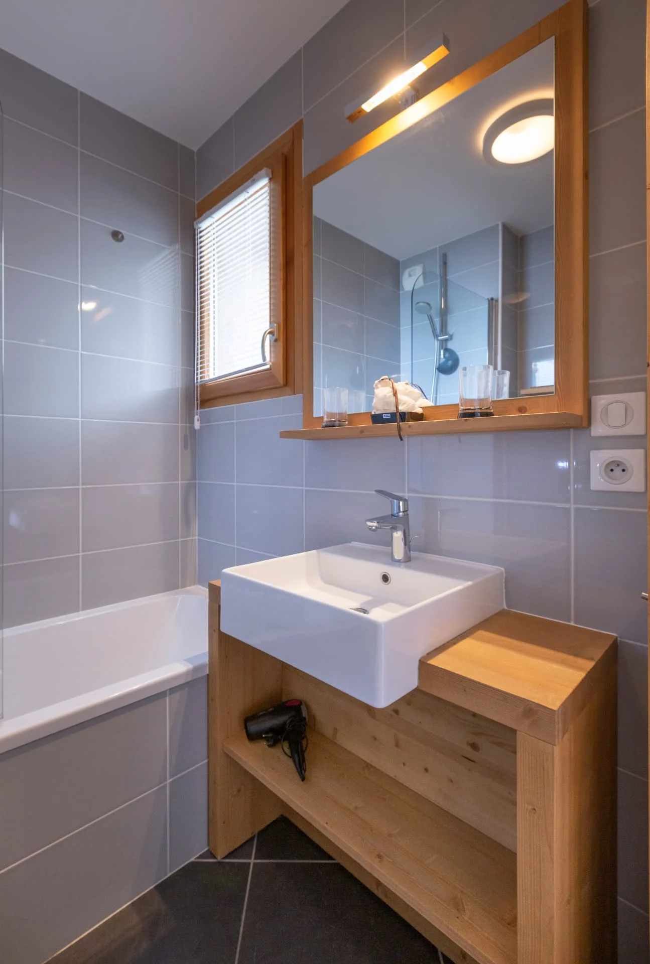Salle de bain de l'appartement Chardonnet avec baignoire et vasque sur meuble en bois