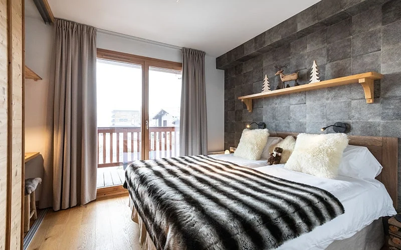 Chambre avec lits jumeaux de l'appartement Petit Bois ouverte sur le balcon côté pistes