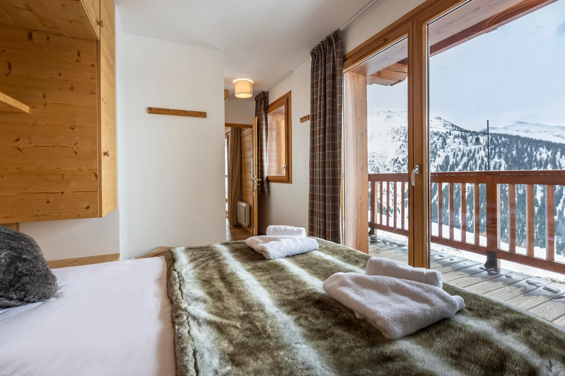 Chambre avec lit double de l'appartement Lièvre Blanc ouverte sur le balcon et les pistes
