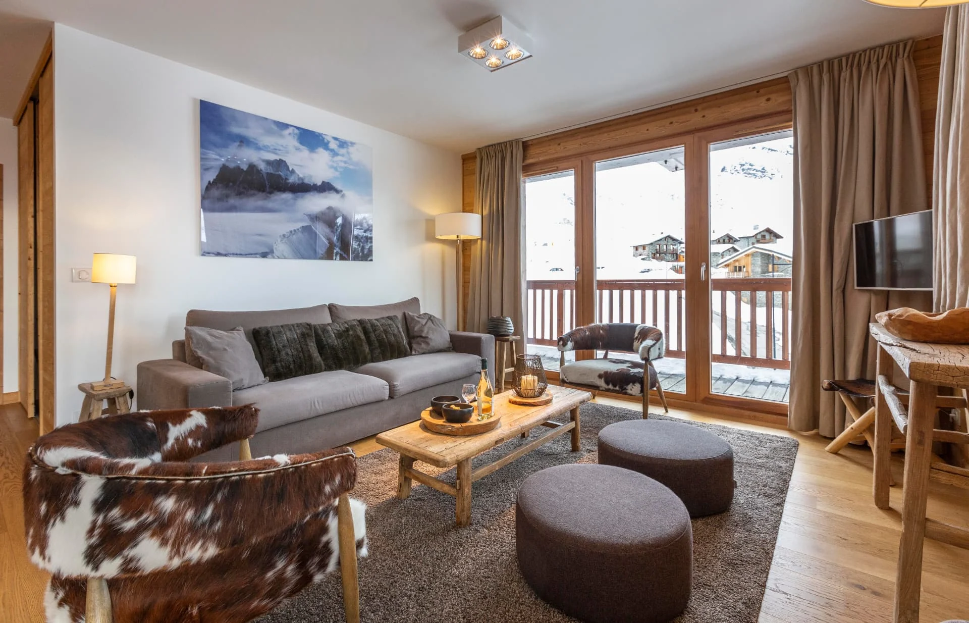 Salon de l'appartement Lauzes avec fauteuils en peau et terrasse sur le hameau des Eucherts