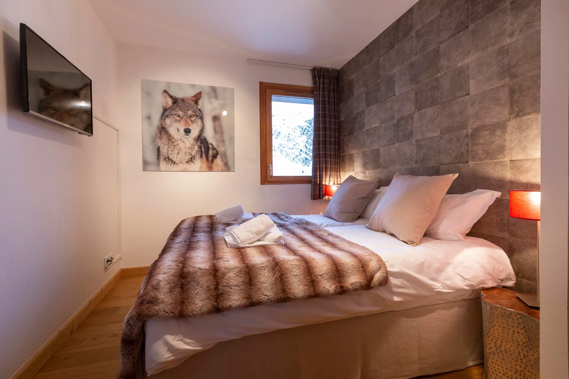 Chambre avec lit double de l'appartement Primavera décorée d'une photographie de loup