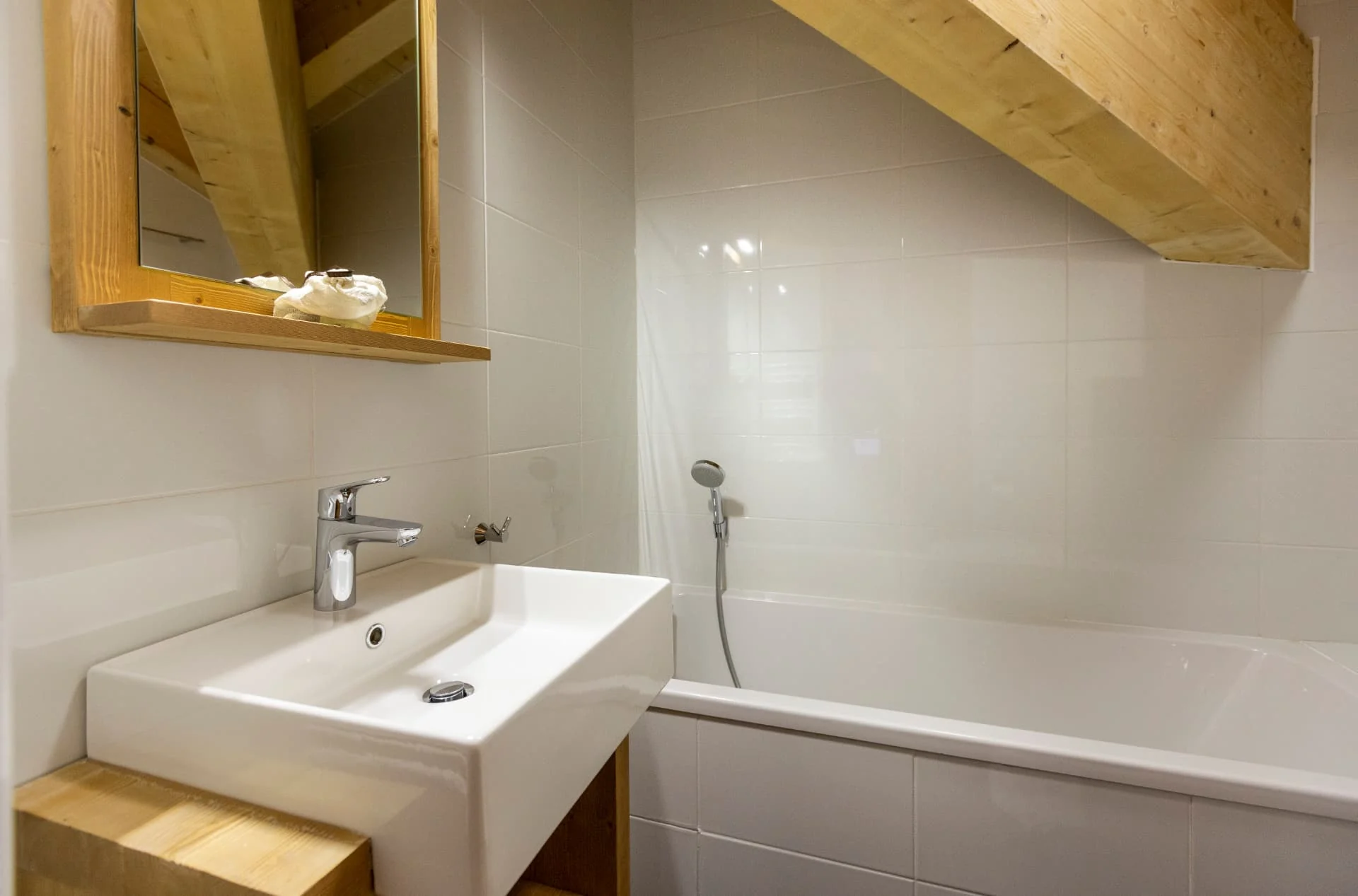 Salle de bain de l'appartement Belvédère avec baignoire sous charpente apparente