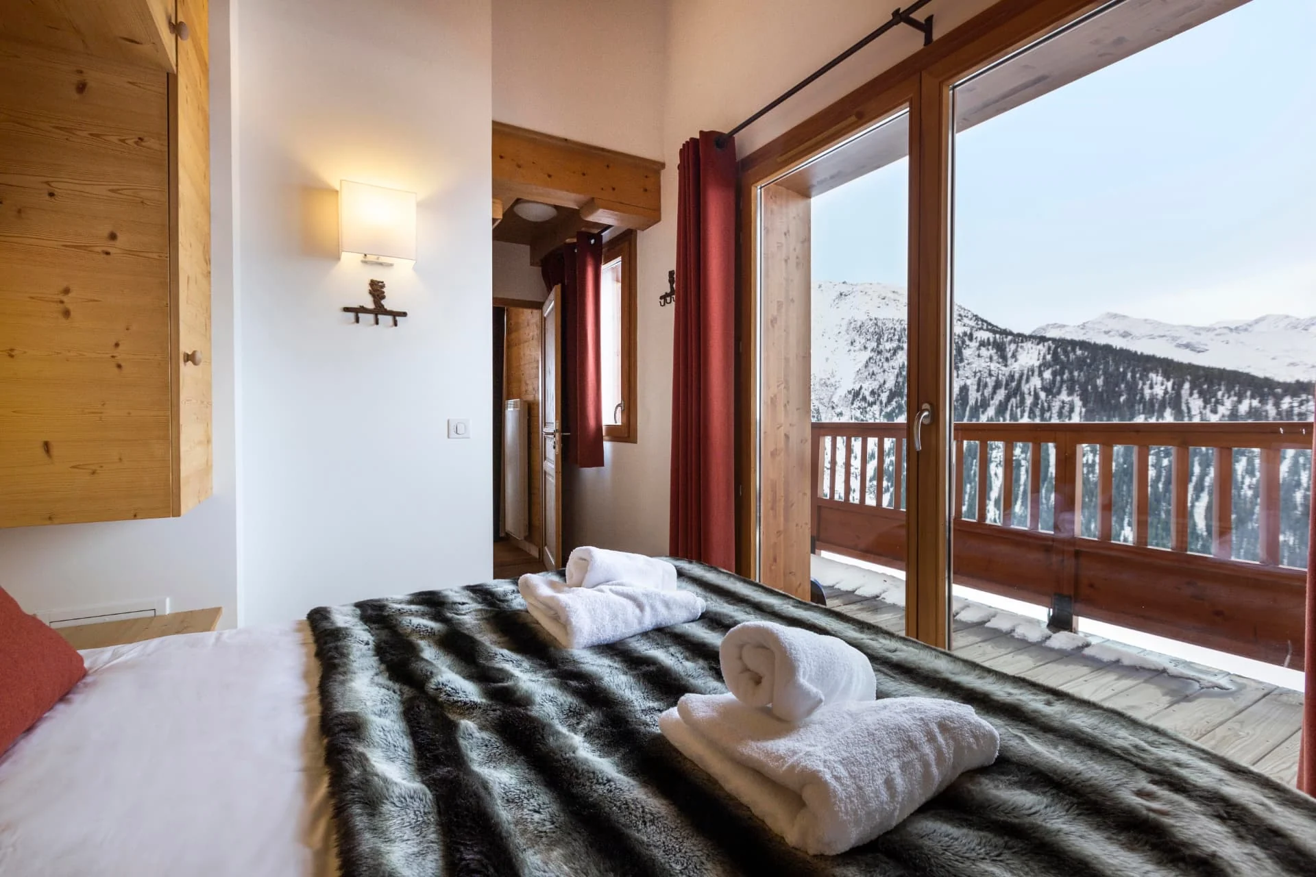 Chambre de l'appartement San Bernardo avec accès balcon et vue sur les montagnes enneigées