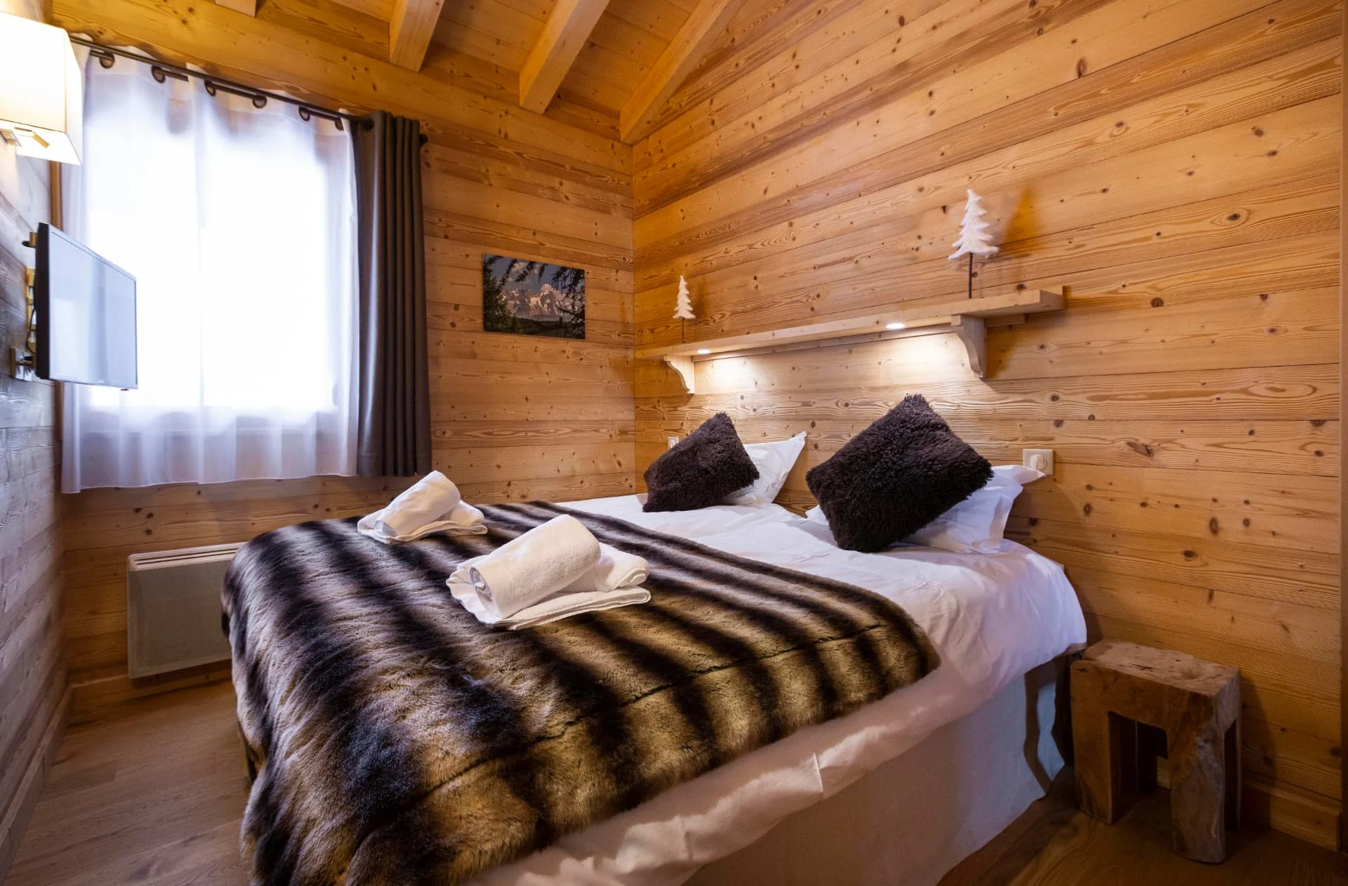 Chambre de l'appartement San Bernardo avec lit double, télévision et murs en bois