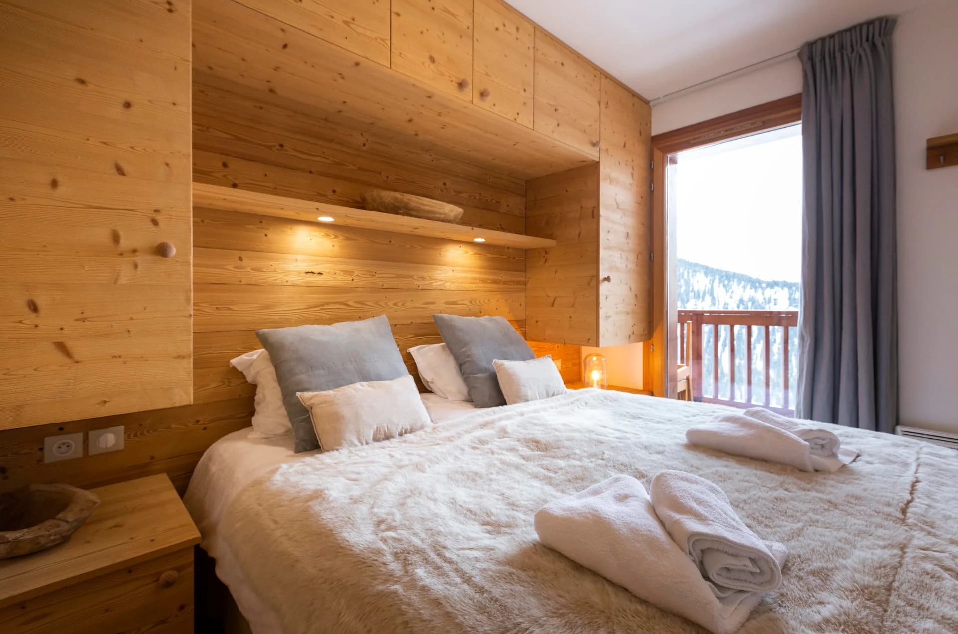 Chambre de l'appartement Lauzes avec lit double, boiseries en vieux bois et accès balcon