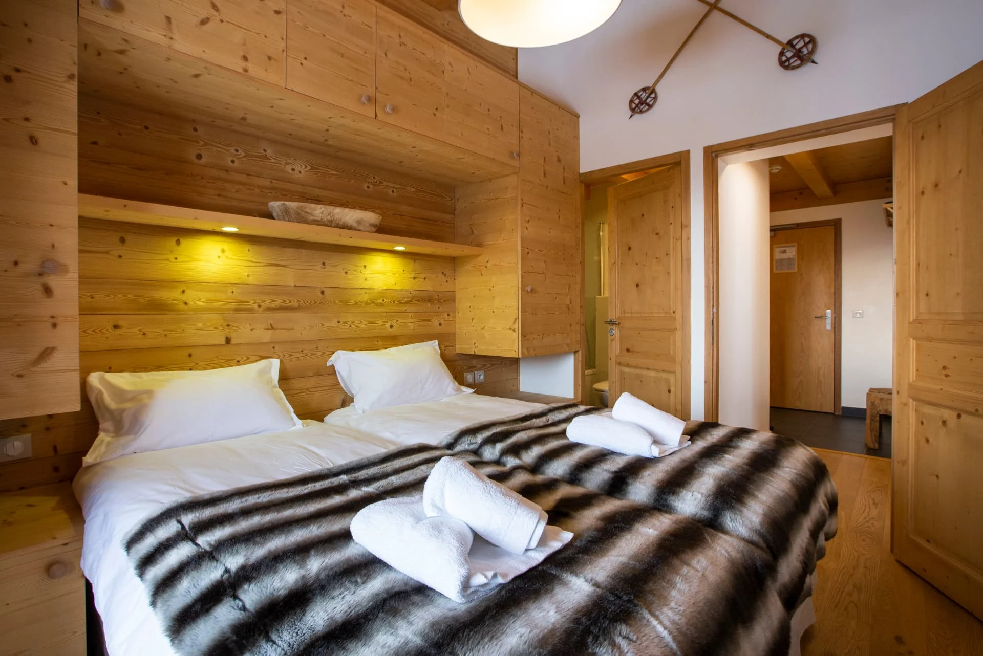 Chambre avec lits jumeaux et tête de lit en bois de l'appartement Bellecombe