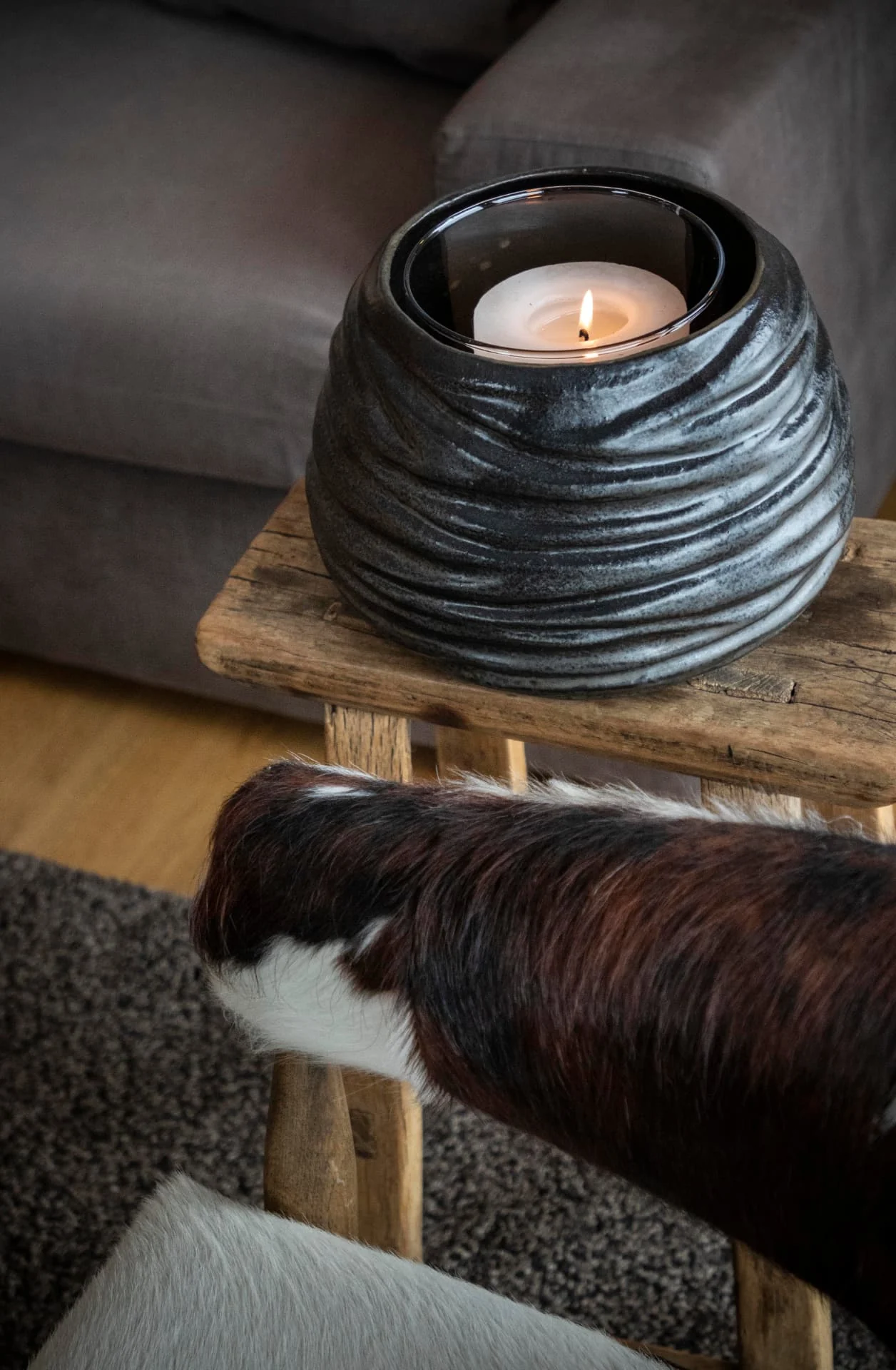 Détail d'une bougie sur un tabouret en bois dans le salon de l'appartement Lauzes