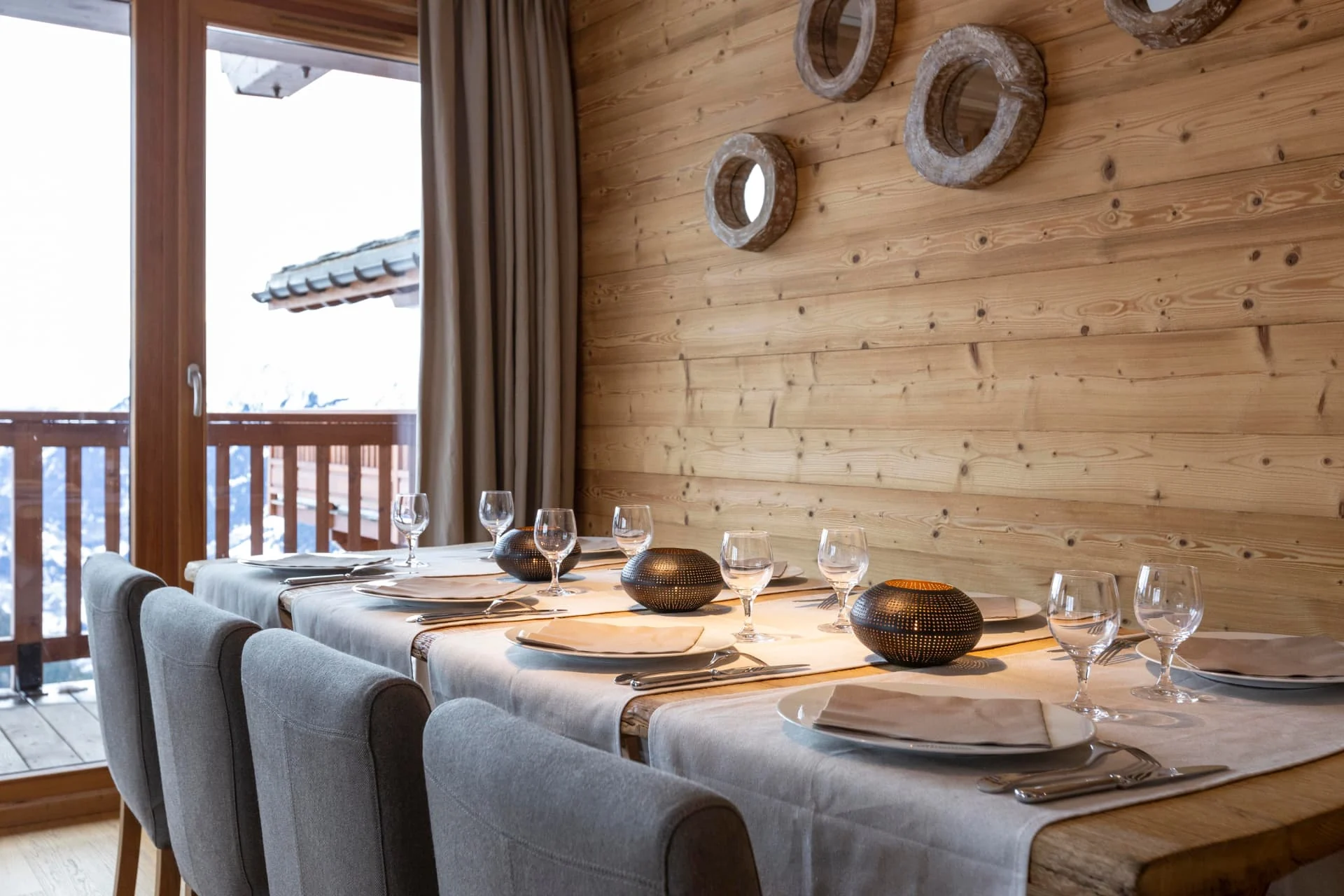 Table dressée de l'appartement Lauzes devant la baie vitrée et la vue sur la Tarentaise